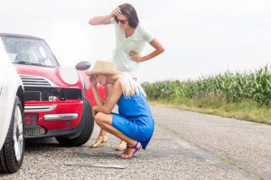 Tensed women looking at damaged cars on road against clear sky